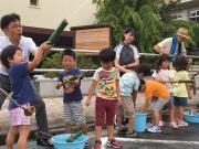 打ち水大作戦で竹の水鉄砲を子どもたちと打つ中小路市長