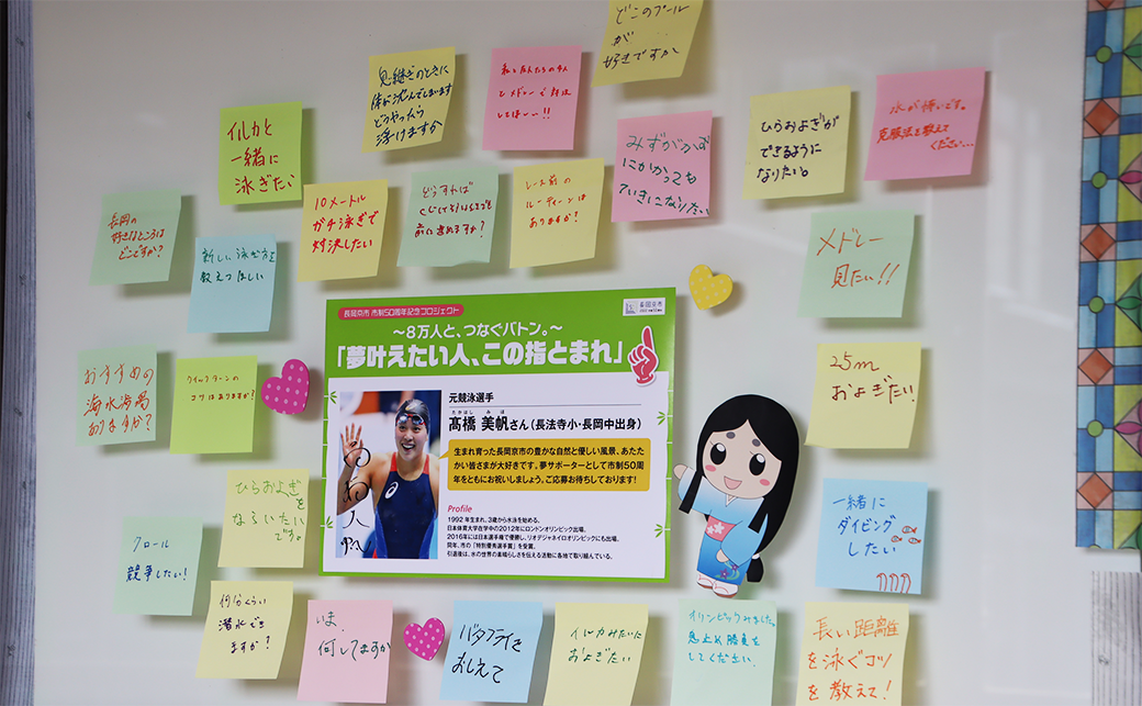 市役所でのサブウェイセラピーの様子。中心に髙橋美帆さんの写真と紹介文が書いてあるパネルがある。パネルの周りに想いが書かれた付箋が貼られている。
