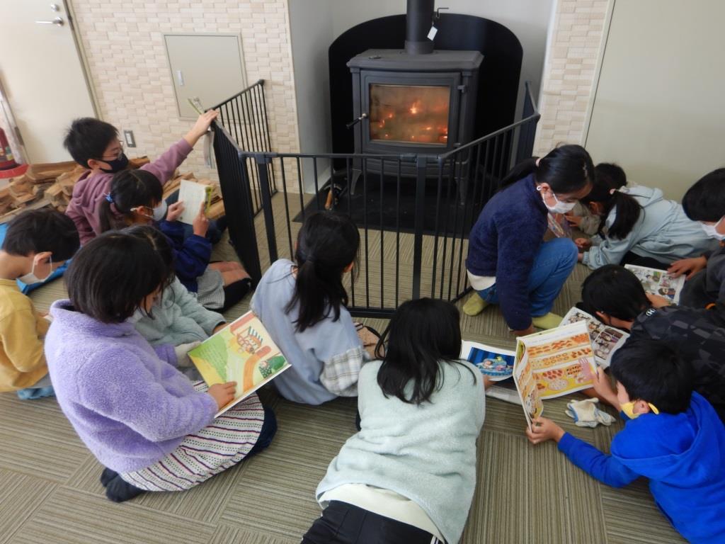 薪ストーブの前で本を読む小学生