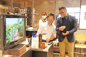 左側に同時通訳しながら解説するバイヤーの永田陽介さん、右側にエステバンさんが写っている写真です